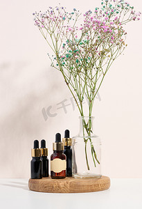 纸管样机摄影照片_棕色玻璃瓶，木制讲台上有移液器和一束花。