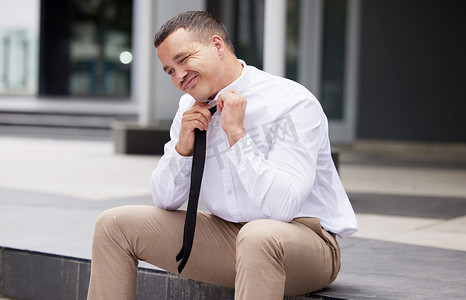 一位年轻的混血商人坐在外面脱下领带。