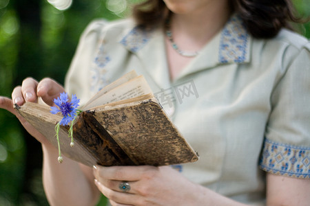 一个穿着复古裙子的年轻女孩拿着旧书