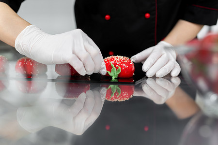 慕斯蛋糕蛋糕摄影照片_糕点师把红色的慕斯蛋糕装饰得像草莓一样