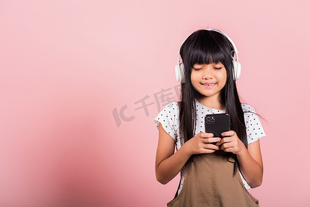手机听音乐摄影照片_亚洲孩子 10 岁享受手机听音乐戴无线耳机闭眼