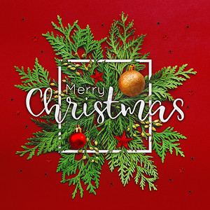 红色文字背景摄影照片_圣诞节背景与崖柏树枝和白色方框中的文字圣诞快乐。