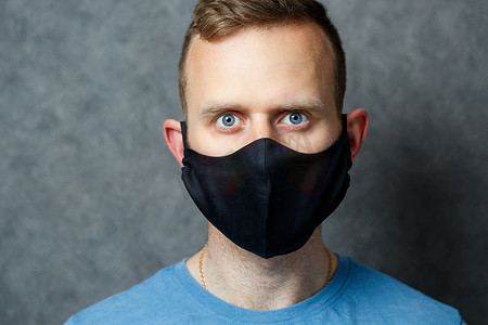 保护抵御摄影照片_戴着黑色防护医用面具的年轻人可以抵御病毒。