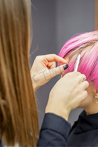 美发师为一名年轻女子染成粉色短发，准备在美容院进行手术。