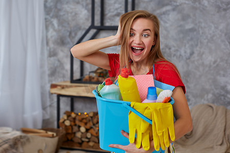 房屋设施摄影照片_一位清洁女工站在客厅里，手里拿着一个装满化学品和整理设施的蓝色桶