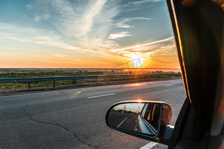 在黄金时段的日落日出时乘汽车在高速公路上旅行的晚上旅行。