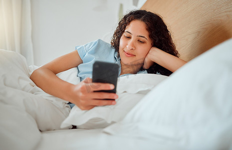 早上，一位女士在床上发短信、查看信息、拿着手机阅读短信，睡不着觉。
