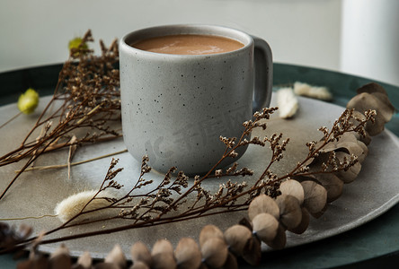 甜茶摄影照片_蓝色陶瓷杯中的热橙奶茶、陶瓷上的甜茶泰式奶茶和陶瓷盘上的干花。
