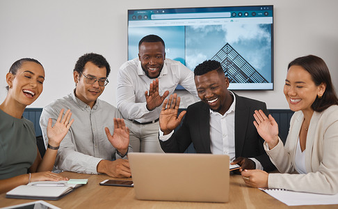 在办公室会议室的笔记本电脑上进行虚拟电话会议期间，多元化的企业商人通过笔记本电脑进行视频通话，向同事们挥手致意。