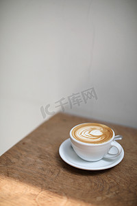 咖啡店木桌上的牛奶制成的卡布奇诺或拿铁艺术咖啡