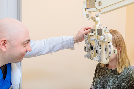 一名男性眼科医生使用验光仪检查一名女孩的视力。