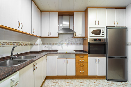旧式空厨房，配有橱柜、瓷砖墙、大理石台面和典型的家用电器
