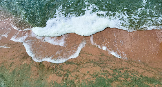 泡沫波和沙子。大风天藻类发出的翡翠波