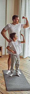 爸爸头摄影照片_运动型父子在室内展示肌肉