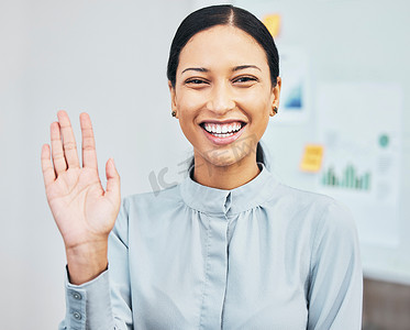 在办公室的虚拟会议中，一位女士通过网络摄像头进行视频通话，一边挥手打招呼，一边介绍、微笑和打手势。