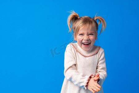 蓝色背景下微笑、大笑的快乐迷人的小女孩