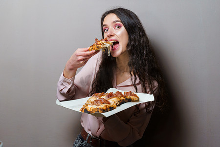 美食评审员召集令摄影照片_女孩快递员在灰色背景下吃 Pinsa 罗马披萨美食意大利美食。