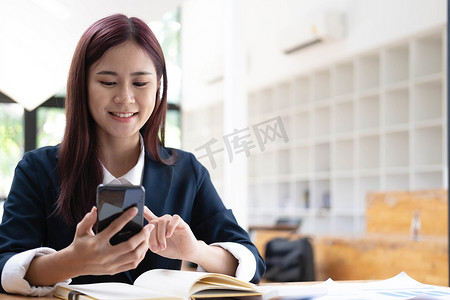 电脑聊天摄影照片_亚洲女性在电话里聊天，在带笑脸的笔记本电脑上工作，商务手机对话，在咖啡馆工作，咖啡馆生活方式，留在咖啡馆，新常态，学习，社交距离。