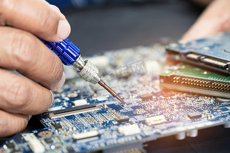 芯片线路摄影照片_技术人员用烙铁修复印刷电路板 PCB 内部。