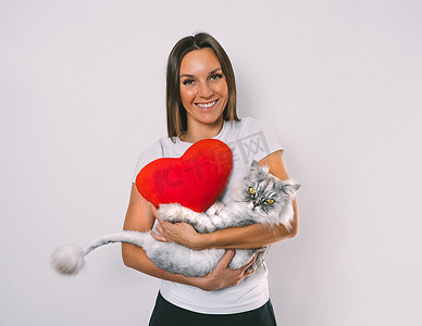 天猫ip摄影照片_抱着红心玩具的女人怀里抱着她可爱的猫。