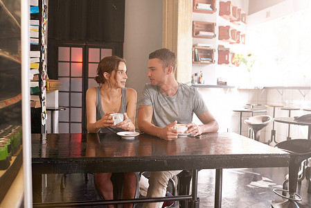 赞美我爱你就像我爱早晨的咖啡一样……一对年轻夫妇坐在咖啡店里。