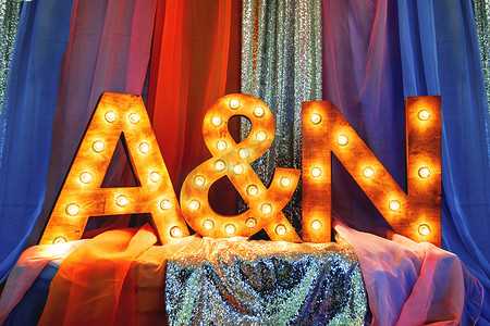 婚礼、宴会、派对装饰的时尚设计元素-木制字母（新娘和新郎名字的第一个字母），配有灯泡和闪闪发光的面料。
