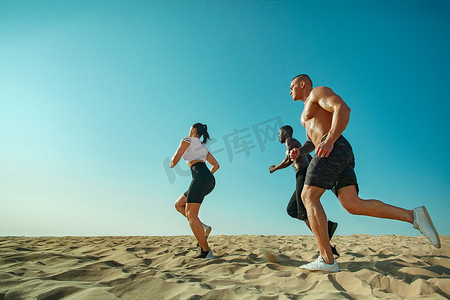 奔跑的运动员摄影照片_一群年轻的男女运动员，适合在天空背景下奔跑的运动员。