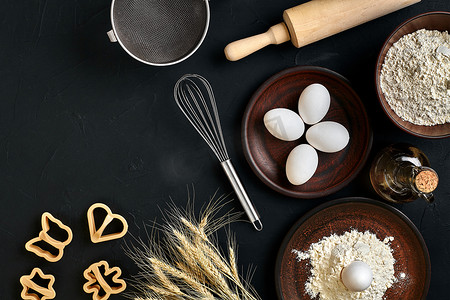 擀面杖摄影照片_面粉、鸡蛋、擀面杖、塑料烘焙模、顶视图，在黑桌上