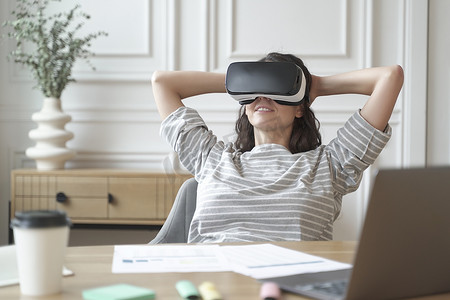 戴着 VR 耳机或头盔观看 360 度视频或电影的轻松的年轻女上班族