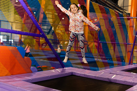 小孩跳摄影照片_小孩在室内操场的蹦床上跳跃。