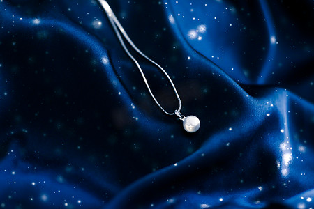 深蓝色丝绸上的豪华白金珍珠项链，假日冬季魔法珠宝礼物