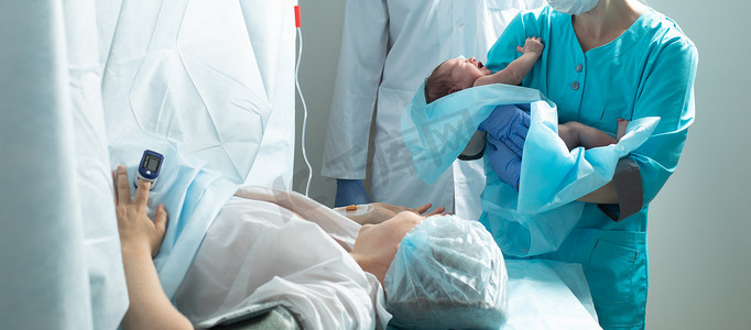 护士在医院里抱着刚出生的婴儿靠近母亲