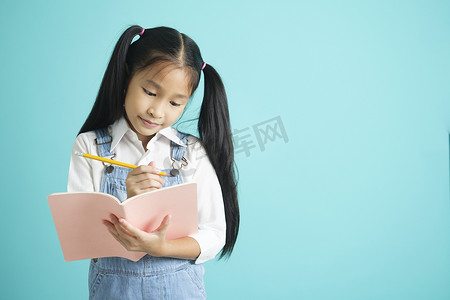 戴着眼镜和教育理念的微笑小女孩拿着课本、阅读、思考和写作。