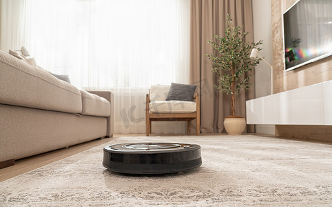 地毯摄影照片_用吸尘器机器人清洁现代公寓的地毯
