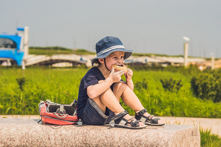 孩子吃零食摄影照片_一个男孩在公园的长椅上吃零食