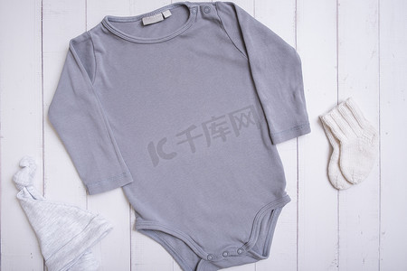 灰色婴儿紧身衣模型，用于木质背景上的徽标、文字或设计，带帽子和袜子顶视图