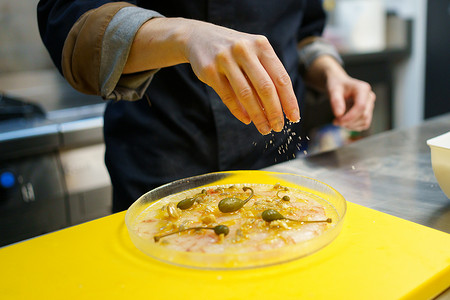 农作物厨师用刺山柑装饰虾生牛肉片