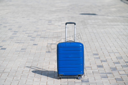 人行道上轮子上的蓝色手提箱。
