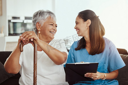 高级护理、医疗保险和护理人员妇女与老年妇女患者坐在一起，一边享受退休之家的乐趣，一边谈笑风生。