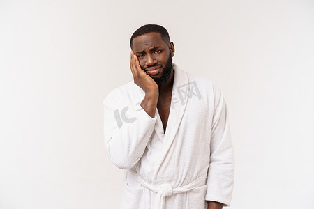 年轻的非洲裔美国人穿着浴袍，在孤立的白色背景下思考，看起来疲惫不堪，对抑郁症问题感到厌烦。