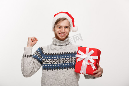 圣诞节概念-有胡子的快乐的年轻人拿着礼物和手隔离在白色背景。
