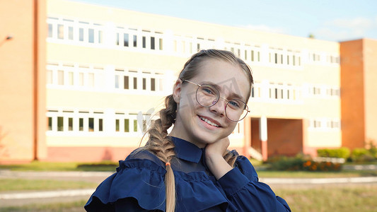 一名戴眼镜的少女在学校门前。