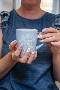 一位年轻女子拿着一杯蓝色咖啡，美丽的夏日美甲