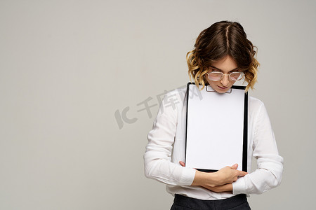 身穿浅色衬衫的女商人和一个文件夹，手里拿着文件，裁剪了工作视图