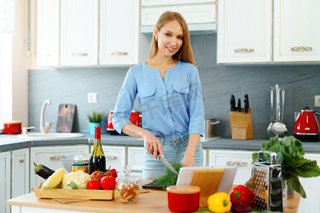 年轻的金发白人女性在厨房里切蔬菜做沙拉