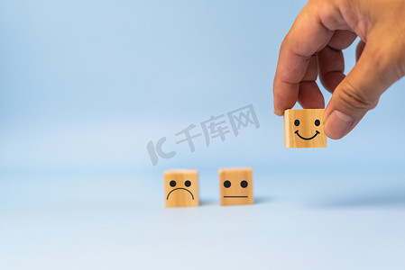 客户服务和满意度概念快乐笑脸图标。业务反馈积极评价给桌子上的木立方体留下了深刻的印象。
