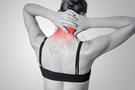 颈部疼痛摄影照片_灰色背景下肩膀或颈部疼痛的年轻女性的特写视图。