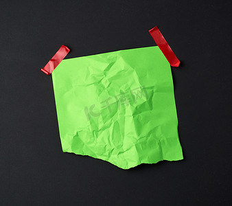 用橡胶红色胶带粘着的绿色皱巴巴的纸片