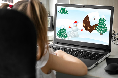 关于冬天摄影照片_一个孩子在笔记本电脑上看关于冬天的卡通片