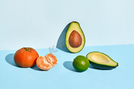 本子样机摄影照片_双色背景下新鲜水果、柑橘石灰和两半切鳄梨的组合物